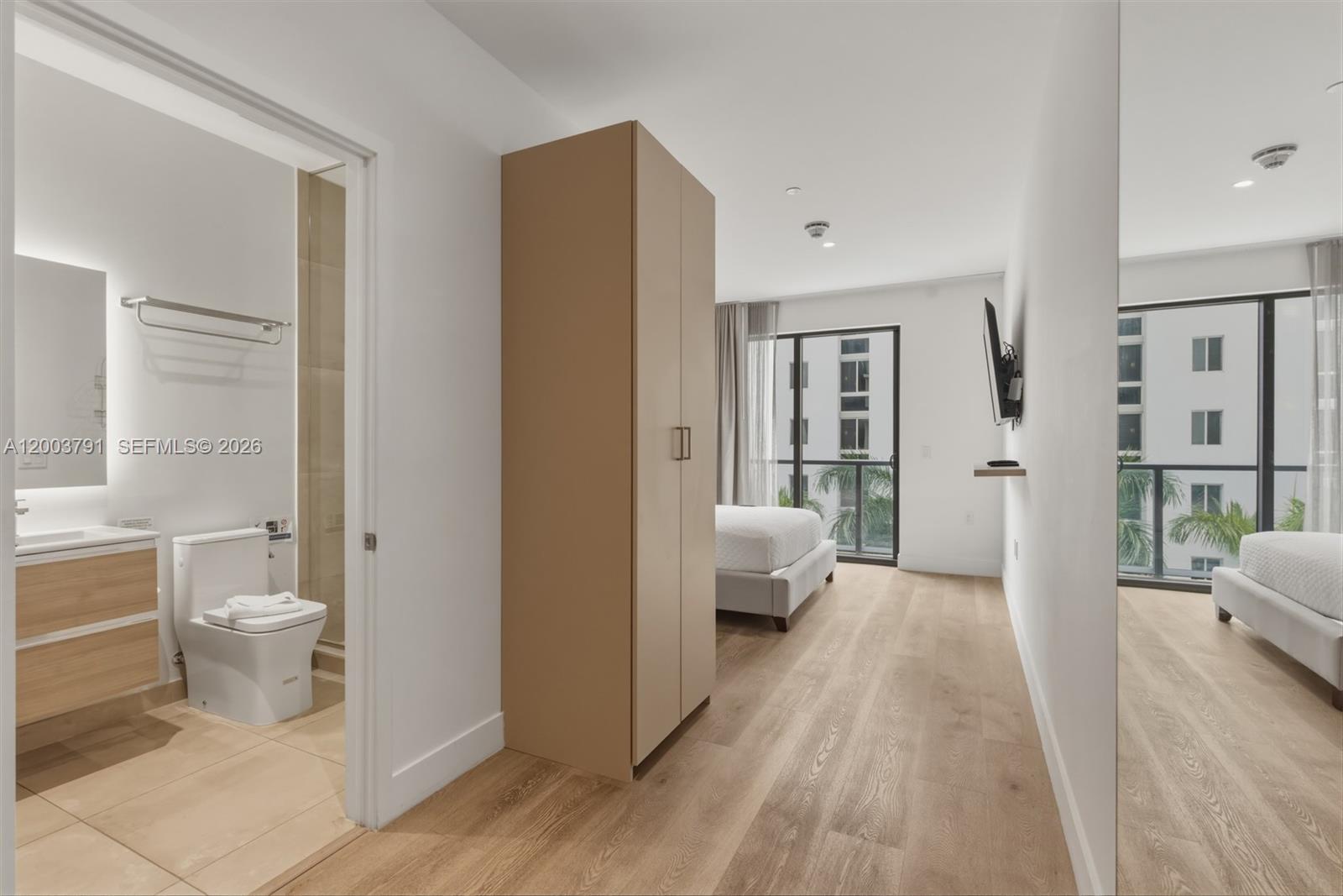 A bedroom with light wood flooring, a tall wardrobe, and an attached bathroom — 229 SW 9th St # 502, Miami FL 33130, MIAMI, FL