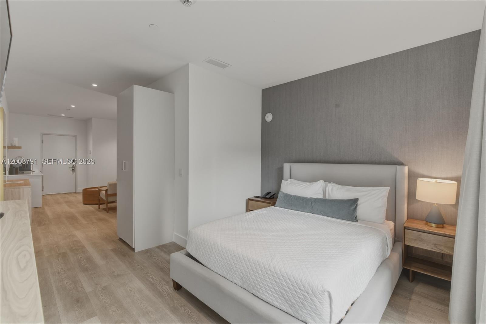 A bedroom features a gray upholstered bed, a textured accent wall, and light wood flooring — 229 SW 9th St # 502, Miami FL 33130, MIAMI, FL