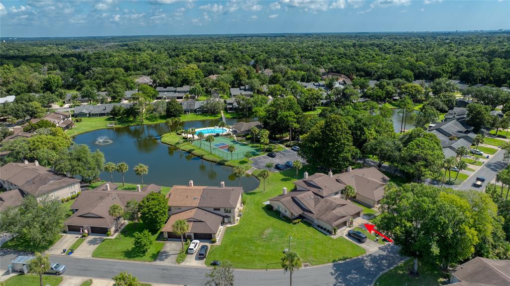 An aerial view shows a residential complex with townhomes, a lake, and a tennis court — 105 DEER LAKE CIRCLE, ORMOND BEACH, FL