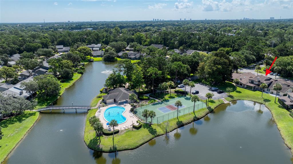 An aerial view shows a residential complex with a pool, tennis court, and lake — 105 DEER LAKE CIRCLE, ORMOND BEACH, FL