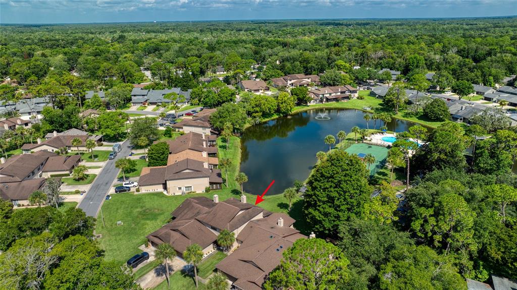 An aerial view shows a multi-unit residential building with brown roofs near a lake — 105 DEER LAKE CIRCLE, ORMOND BEACH, FL