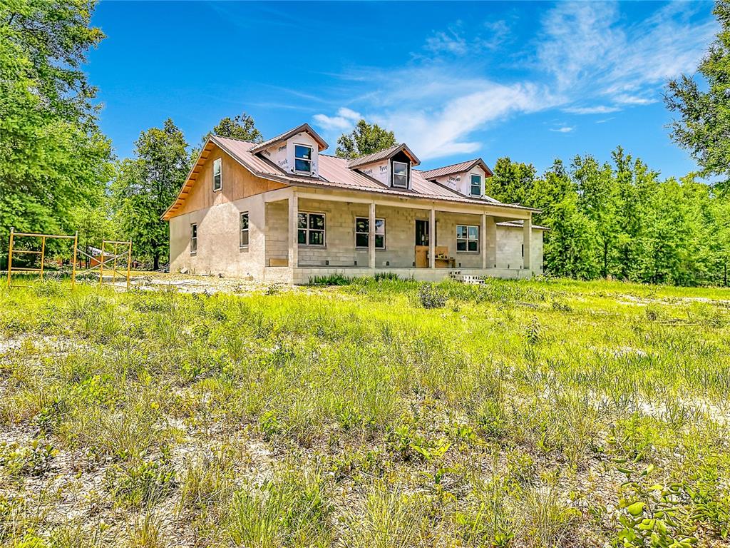 A partially constructed house with a metal roof and concrete block walls sits in a field — 2916 SW ICHETUCKNEE AVENUE, LAKE CITY, FL