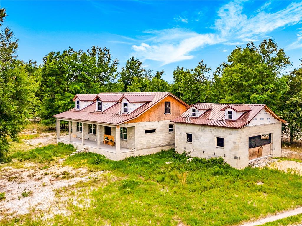 An unfinished house with a metal roof and concrete block walls sits in a wooded lot — 2916 SW ICHETUCKNEE AVENUE, LAKE CITY, FL