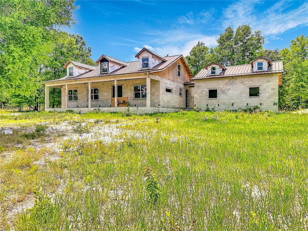 A partially constructed house with a metal roof and concrete block walls sits in a field — 2916 SW ICHETUCKNEE AVENUE, LAKE CITY, FL