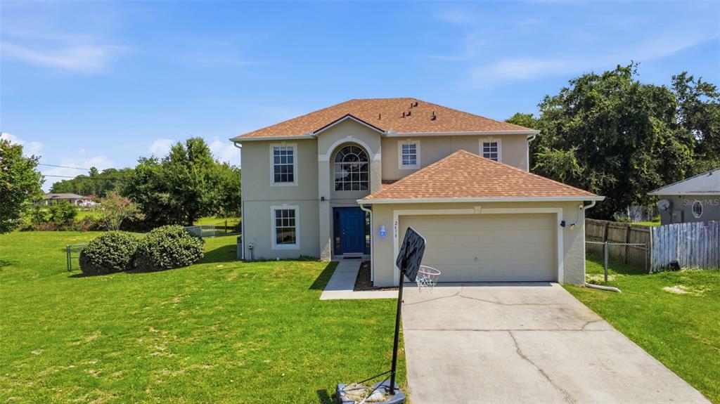 A two-story house with a beige stucco exterior, a blue front door, and a garage — 2678 BECKWITH STREET, DELTONA, FL