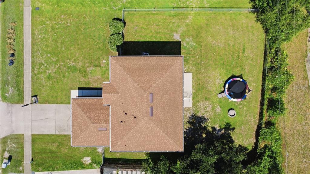 An aerial view shows a house with a brown roof, a backyard trampoline, and driveway — 2678 BECKWITH STREET, DELTONA, FL