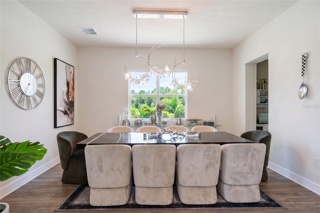 A dining room features a black marble table, upholstered chairs, and a modern chandelier — 8059 LEAF GROVE CIRCLE, ORLANDO, FL