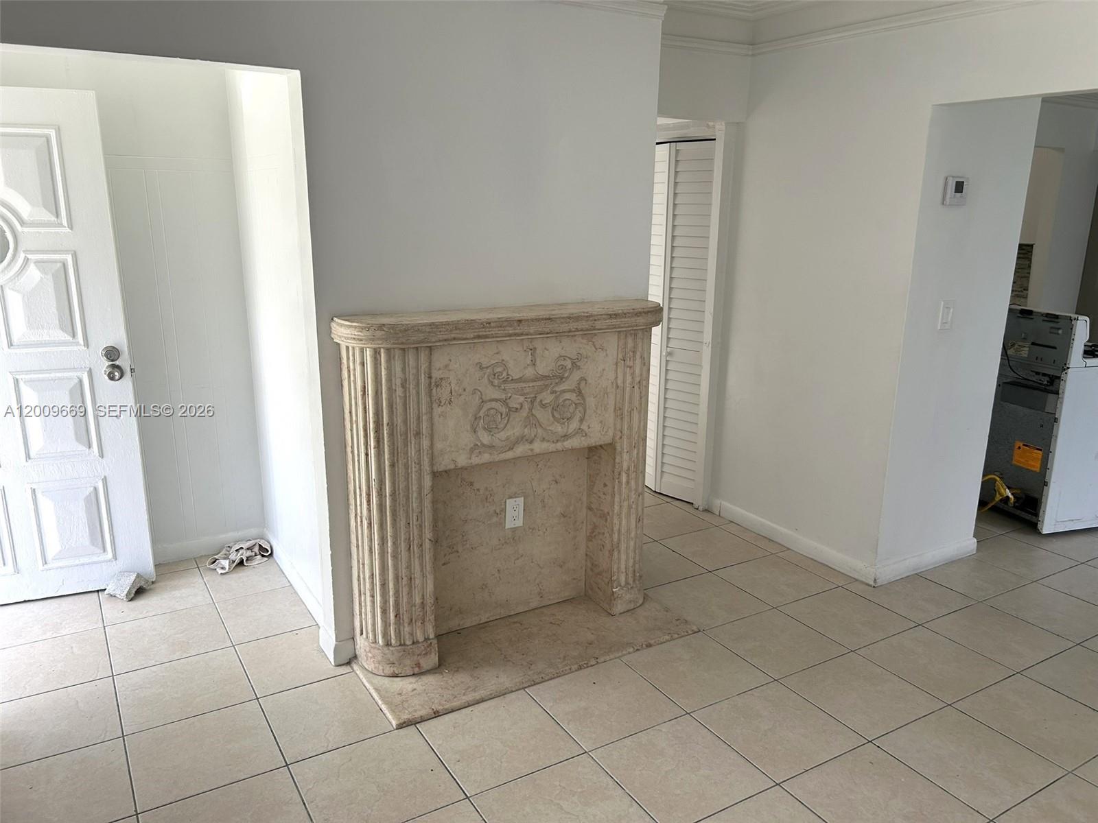 A room features a decorative stone fireplace mantel against a white wall and tiled flooring — 9808 NW 2nd Ave, Miami FL 33150, MIAMI, FL