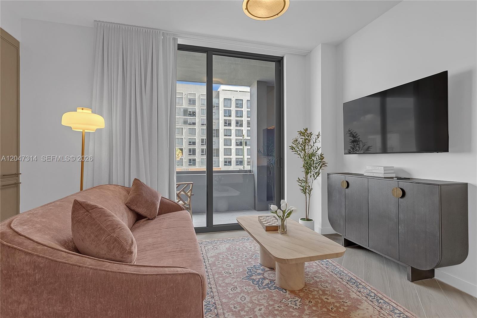 A living room features a pink sofa, a wooden coffee table, and a wall-mounted television — 2700 NW 2nd Ave # 246, Miami FL 33127, MIAMI, FL