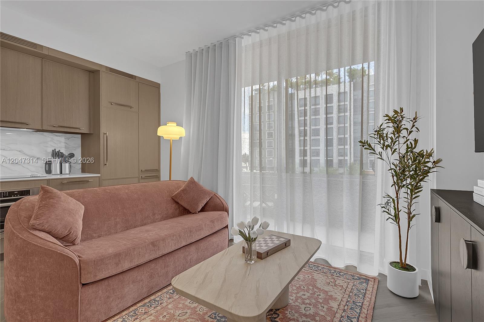 A living room features a pink sofa, a marble coffee table, and a kitchenette — 2700 NW 2nd Ave # 246, Miami FL 33127, MIAMI, FL