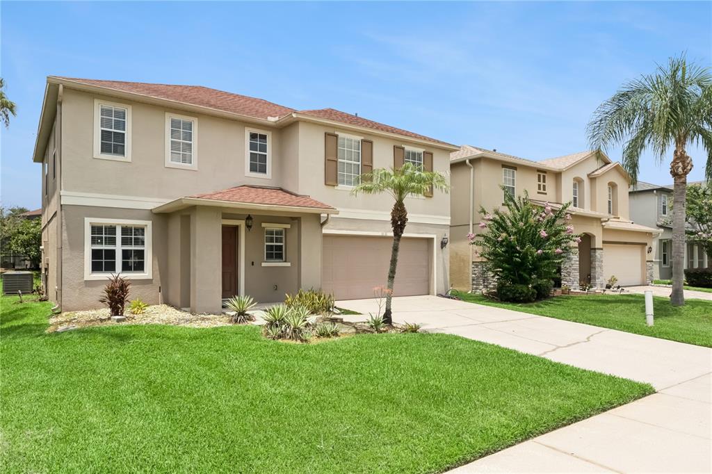 A two-story suburban house with a tan stucco exterior, brown shutters, and a two-car garage — 1830 MORNING SKY DRIVE, WINTER GARDEN, FL