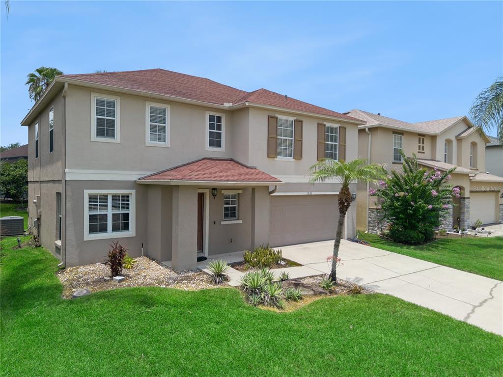 A two-story suburban house with a tan stucco exterior, brown roof, and attached garage — 1830 MORNING SKY DRIVE, WINTER GARDEN, FL