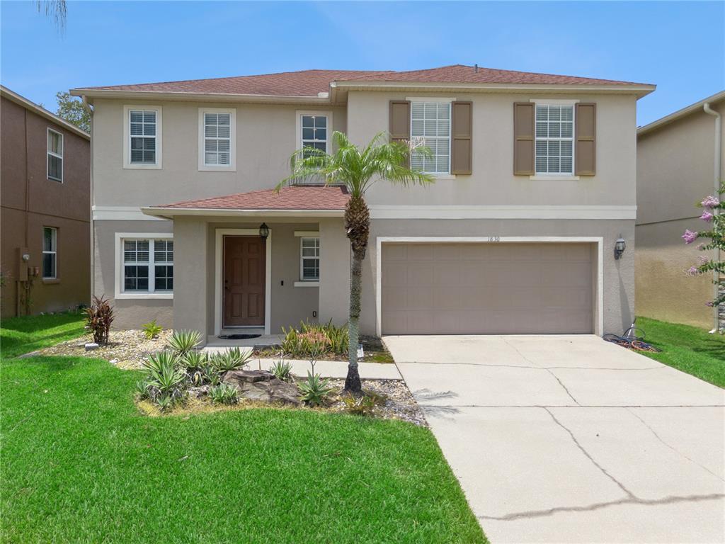 A two-story suburban house with a beige stucco exterior, a brown roof, and a garage — 1830 MORNING SKY DRIVE, WINTER GARDEN, FL