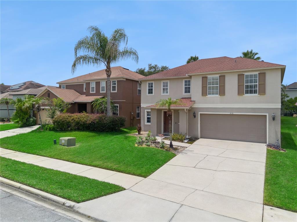 A two-story suburban house with a tan exterior, a two-car garage, and a palm tree — 1830 MORNING SKY DRIVE, WINTER GARDEN, FL