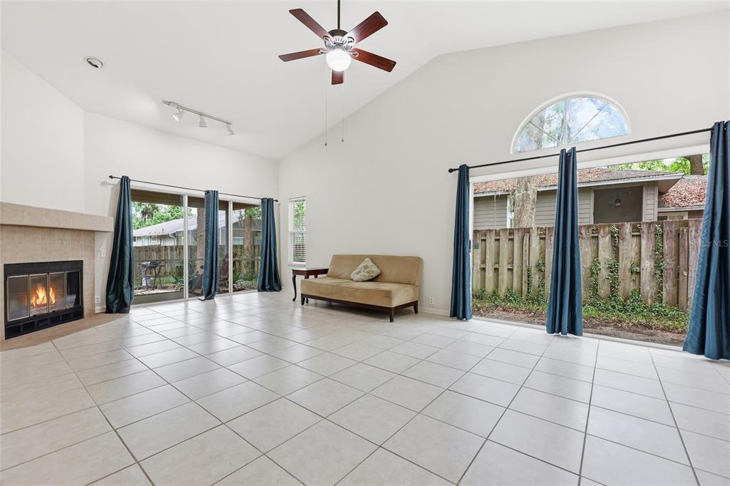 A living room features a fireplace, tile flooring, a vaulted ceiling, and large sliding doors — 1736 NW 16TH PLACE, GAINESVILLE, FL