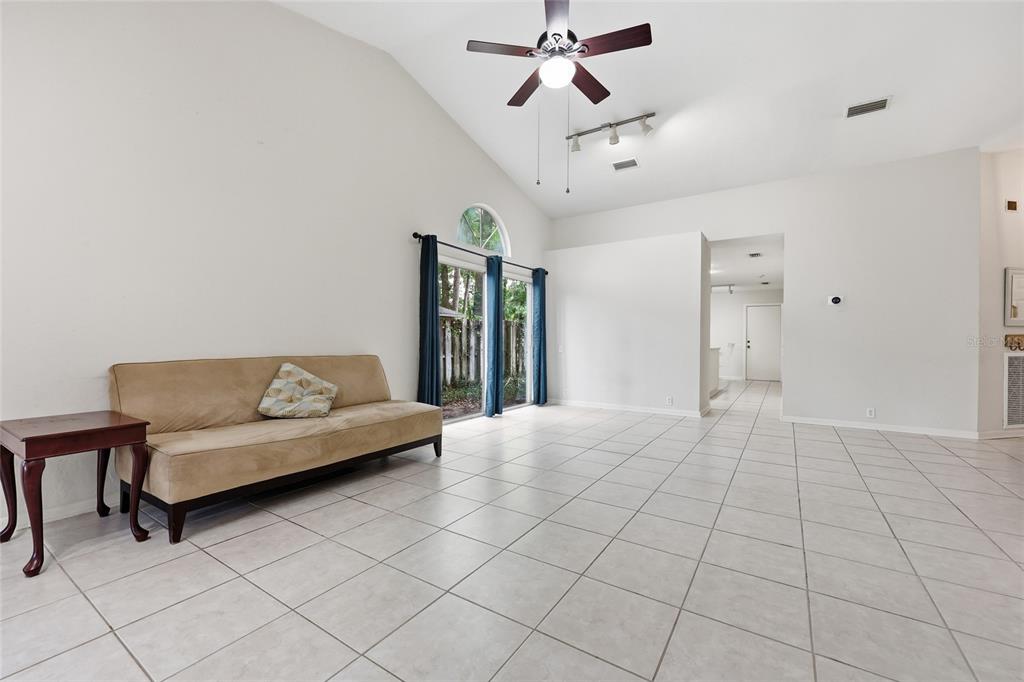 A living room with light tile floors, a vaulted ceiling, and a tan sofa — 1736 NW 16TH PLACE, GAINESVILLE, FL