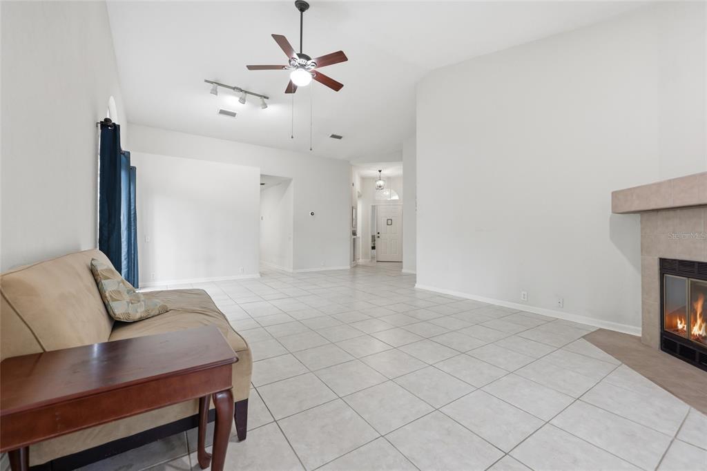 A living room with light tile floors, a ceiling fan, and a fireplace — 1736 NW 16TH PLACE, GAINESVILLE, FL