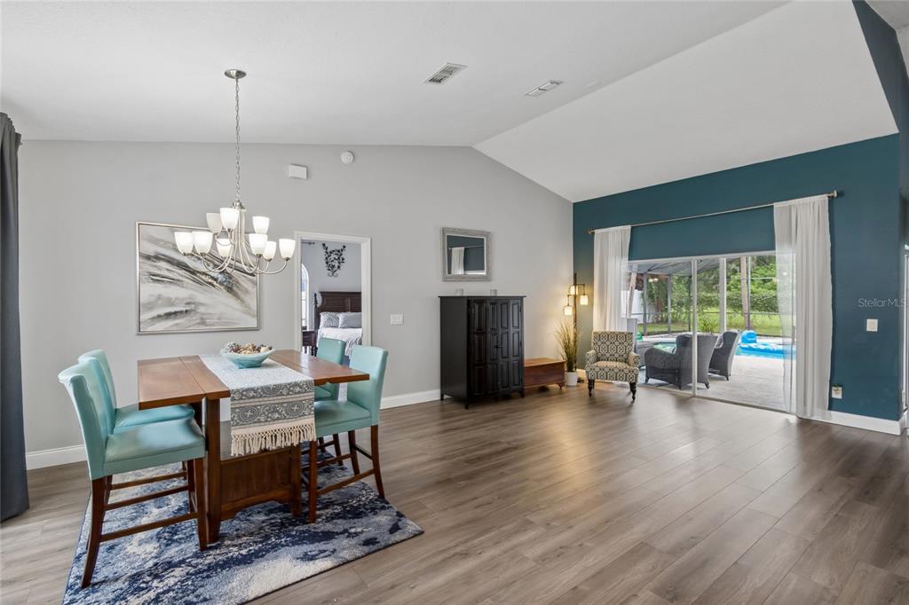A dining area with a wood table and teal chairs opens to a pool patio — 1552 THORNHILL CIRCLE, OVIEDO, FL