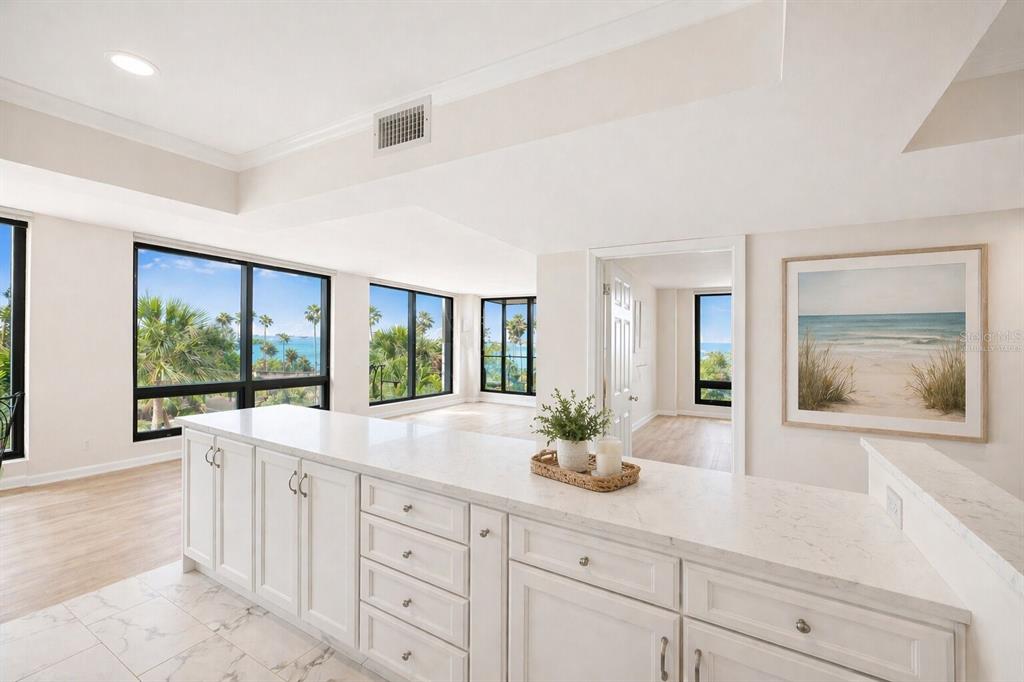An empty room with wood-look flooring and large windows overlooking palm trees and water — 707 S GULFSTREAM AVENUE UNIT 307, SARASOTA, FL