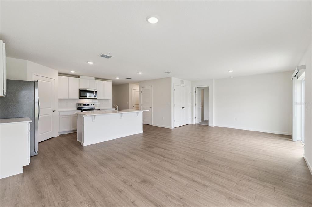 A bright, open-concept kitchen and living area featuring white cabinetry, an island, and wood flooring — 141 HEIRLOOM DRIVE, ORMOND BEACH, FL