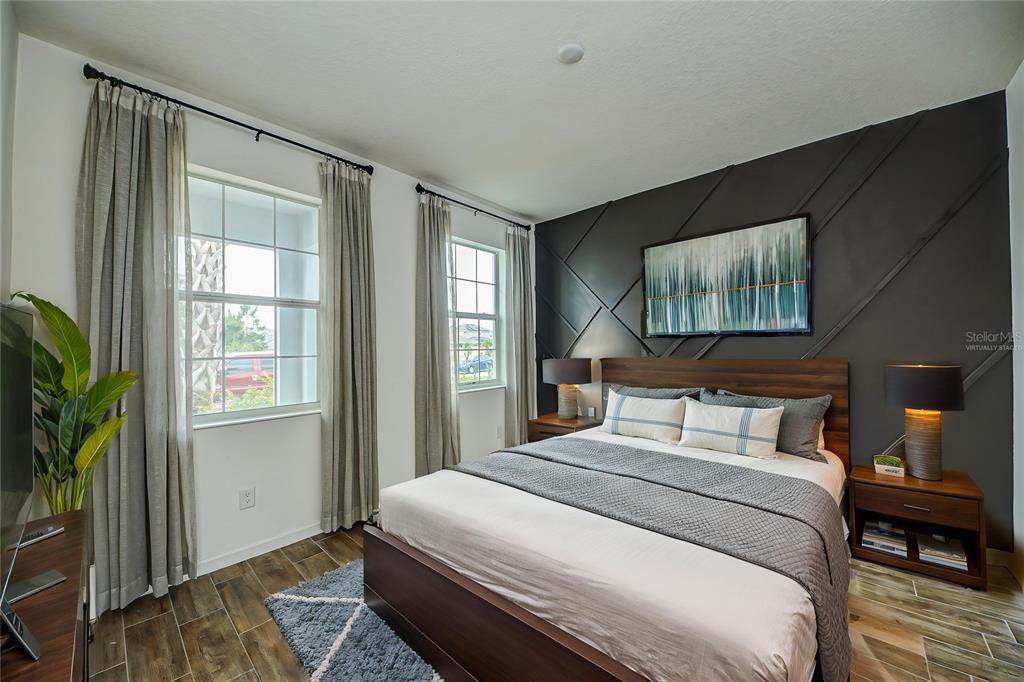 A bedroom features a dark accent wall with geometric molding, a bed, and two windows — 603 FORTUNA DRIVE, DAVENPORT, FL