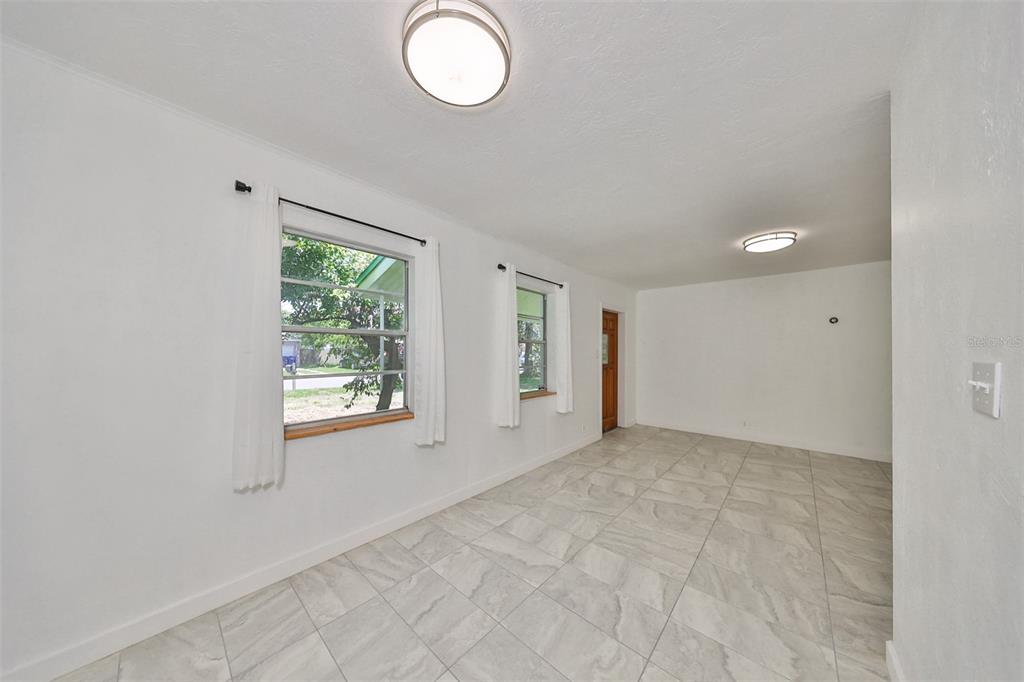An empty room with white walls, tiled floors, two windows, and two ceiling lights — 3908 W WALLACE AVENUE, TAMPA, FL