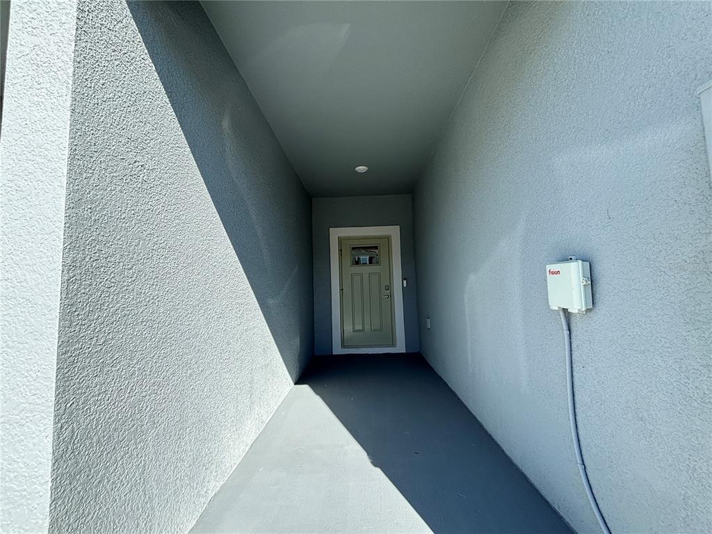A covered entryway features a light green door and a wall-mounted utility box — 36425 CAMPFIRE TERRACE, ZEPHYRHILLS, FL