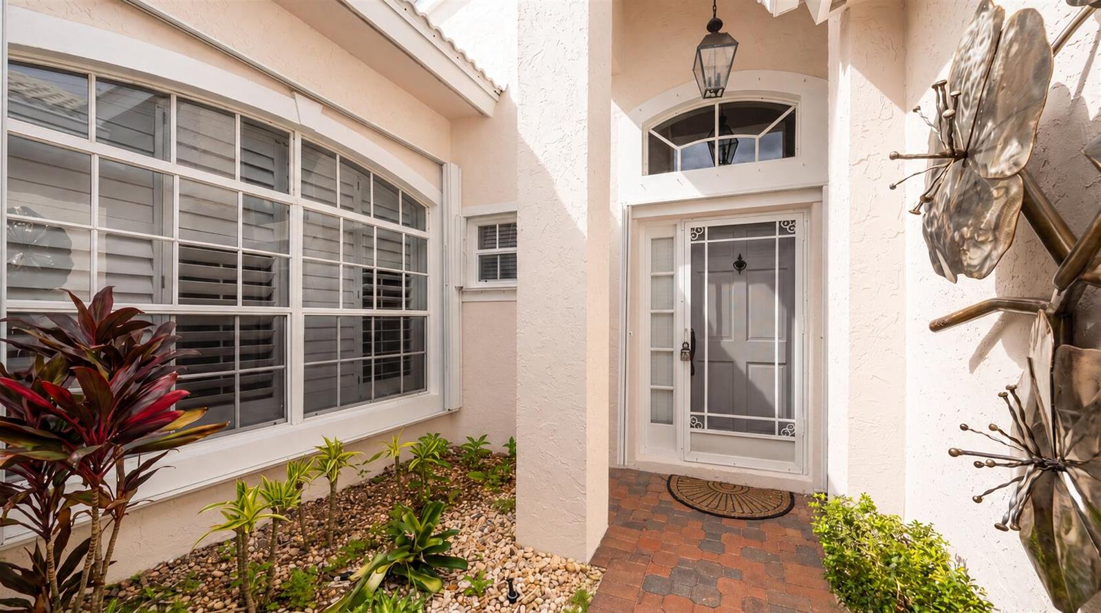 The exterior entryway features a white front door, a brick walkway, and a landscaped garden — 3878 N Longview Drive, Jupiter FL 33477, JUPITER, FL