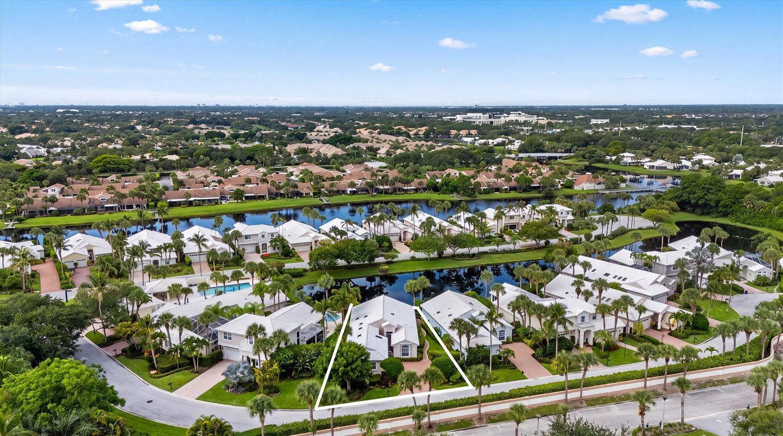 An aerial view shows a residential neighborhood with white houses, palm trees, and a central lake — 3878 N Longview Drive, Jupiter FL 33477, JUPITER, FL