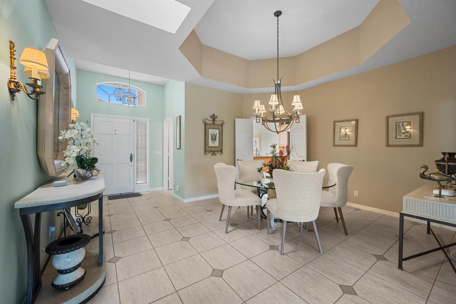 A dining area with a glass table, chandelier, and tile flooring sits near an entryway — 3878 N Longview Drive, Jupiter FL 33477, JUPITER, FL