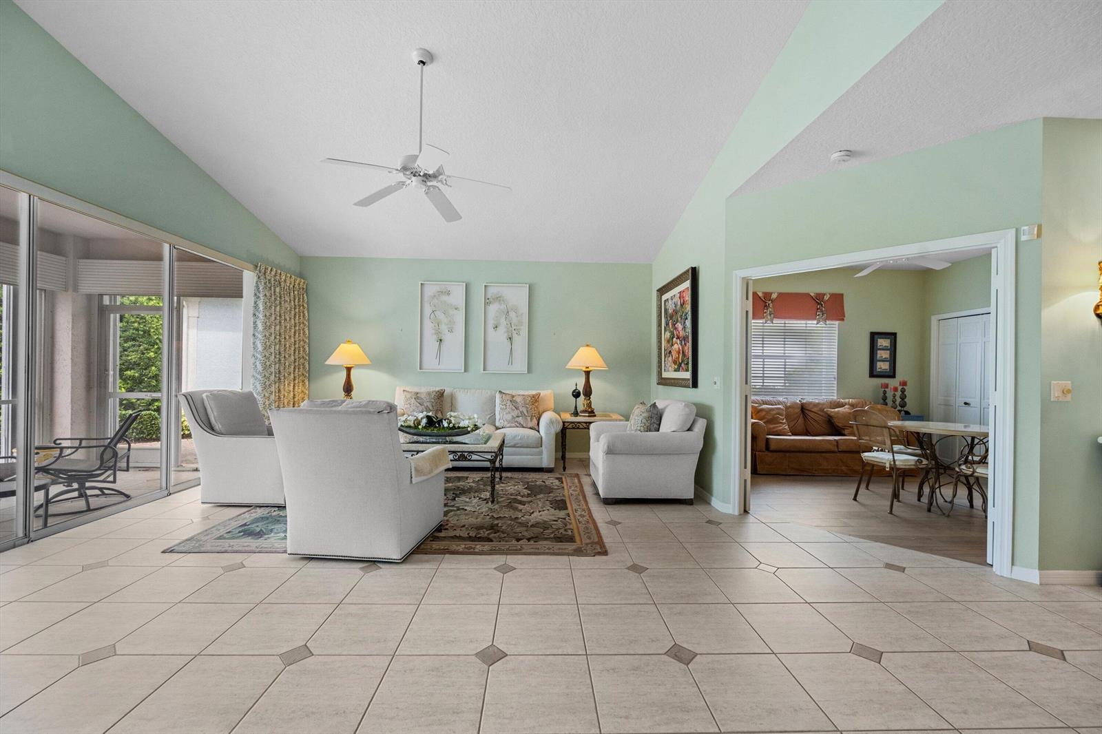 A spacious living room with light green walls, tile flooring, and a vaulted ceiling — 3878 N Longview Drive, Jupiter FL 33477, JUPITER, FL