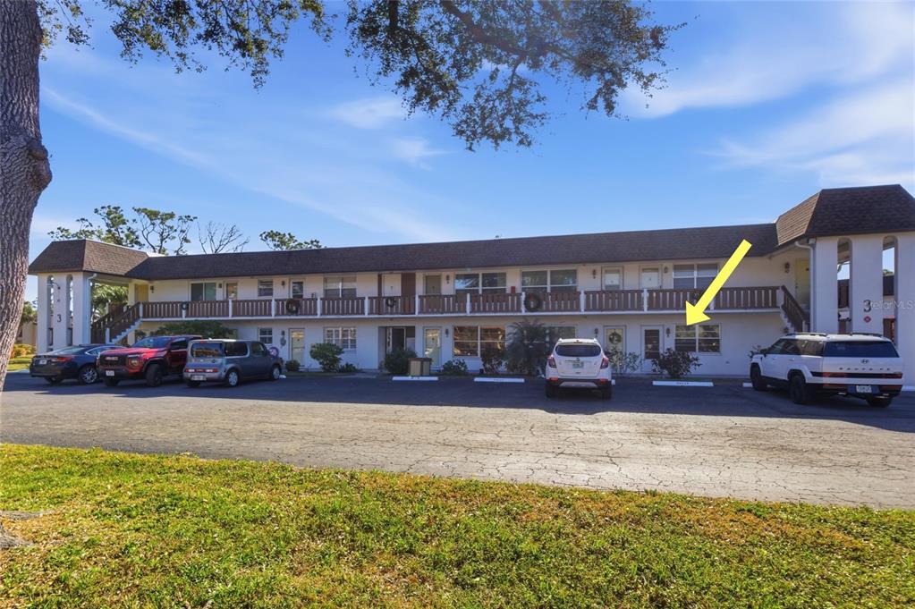 A two-story apartment building exterior features a parking lot and a yellow arrow pointing toward a unit — 3 QUAILS RUN BOULEVARD UNIT 3101(5), ENGLEWOOD, FL