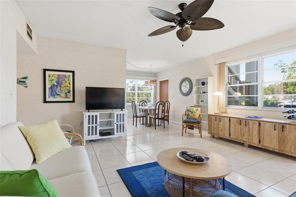 A bright living and dining area features tile floors, a ceiling fan, and large windows — 3 QUAILS RUN BOULEVARD UNIT 3101(5), ENGLEWOOD, FL