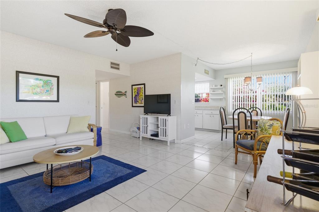A living room and dining area with white tile floors, a ceiling fan, and furniture — 3 QUAILS RUN BOULEVARD UNIT 3101(5), ENGLEWOOD, FL