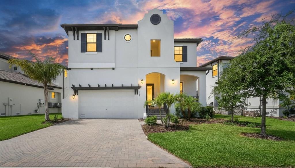 A two-story white stucco house features a paved driveway, a garage, and a front porch — 1108 SEAGRAPE DRIVE, RUSKIN, FL