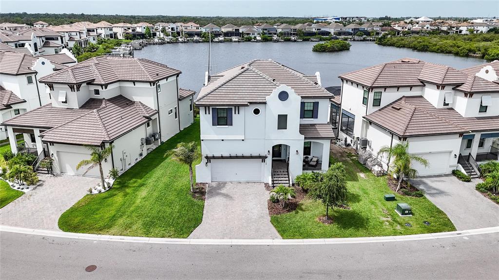 An aerial view shows three suburban houses with tiled roofs situated along a waterfront — 1108 SEAGRAPE DRIVE, RUSKIN, FL