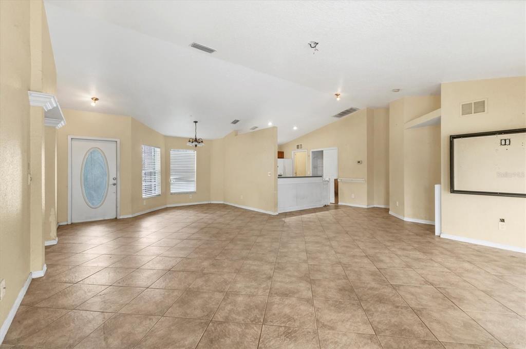 An open-concept living area features beige tile flooring, vaulted ceilings, and a white front door — 11619 SUMMIT ROCK COURT, PARRISH, FL