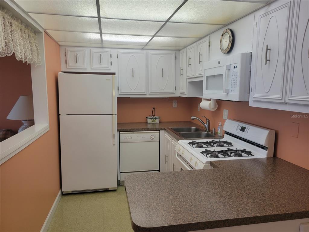 A kitchen features white cabinetry, white appliances, a gas range, and speckled brown countertops — 9950 62ND TERRACE N UNIT 417, ST PETERSBURG, FL
