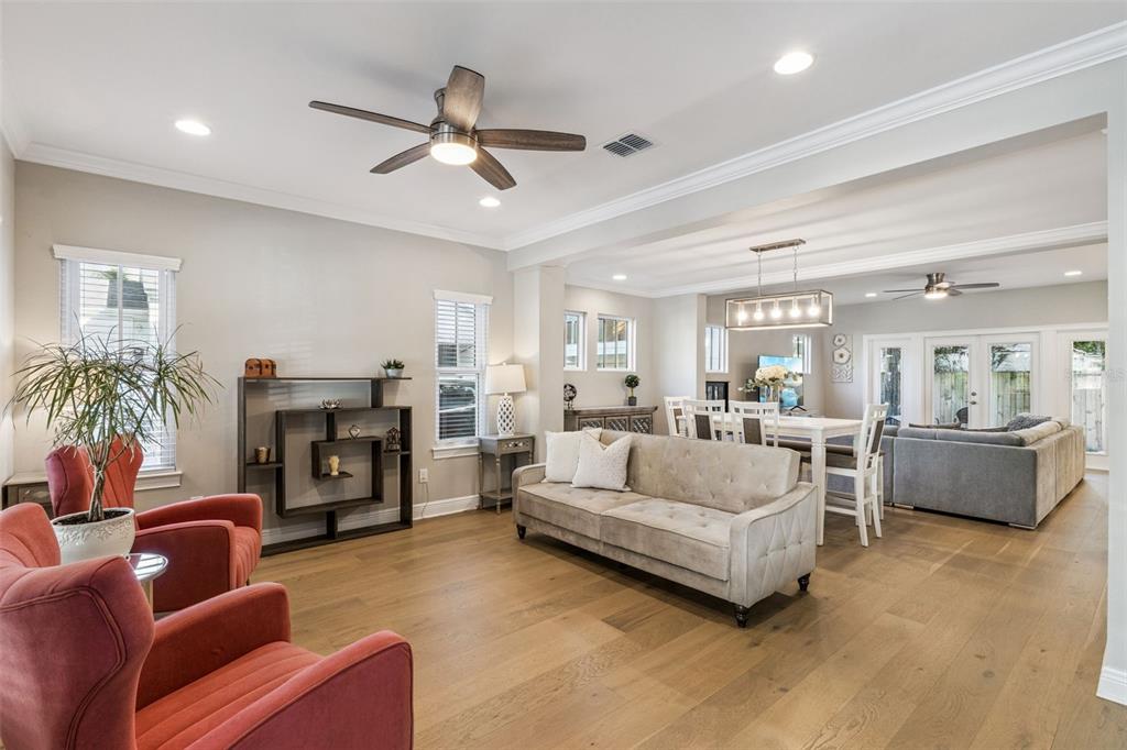 A bright open-concept living and dining area features hardwood floors, a neutral sofa, and armchairs — 210 HIBISCUS COURT, ORLANDO, FL