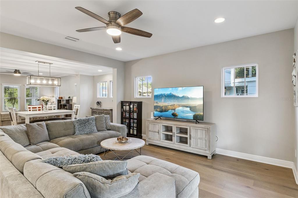 A living room features a grey sectional sofa, a television on a console, and wood flooring — 210 HIBISCUS COURT, ORLANDO, FL