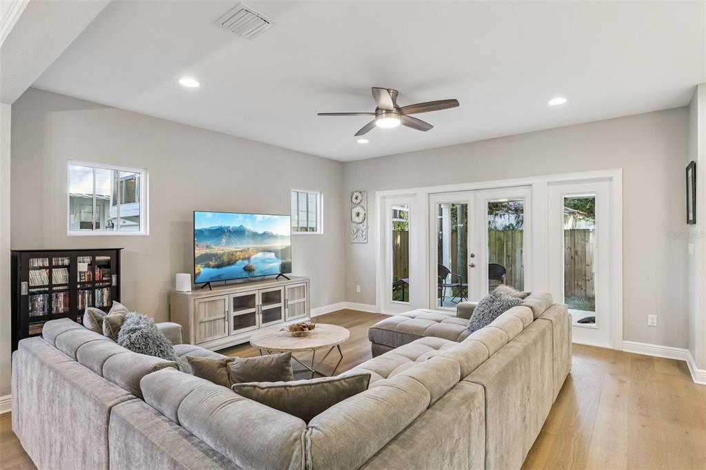 A living room features a large sectional sofa, a television on a console, and glass doors — 210 HIBISCUS COURT, ORLANDO, FL