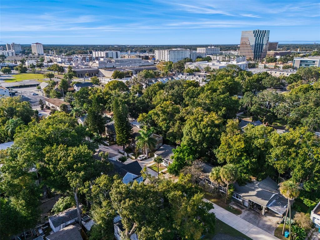 An aerial view shows a residential neighborhood with dense trees and nearby city buildings — 210 HIBISCUS COURT, ORLANDO, FL