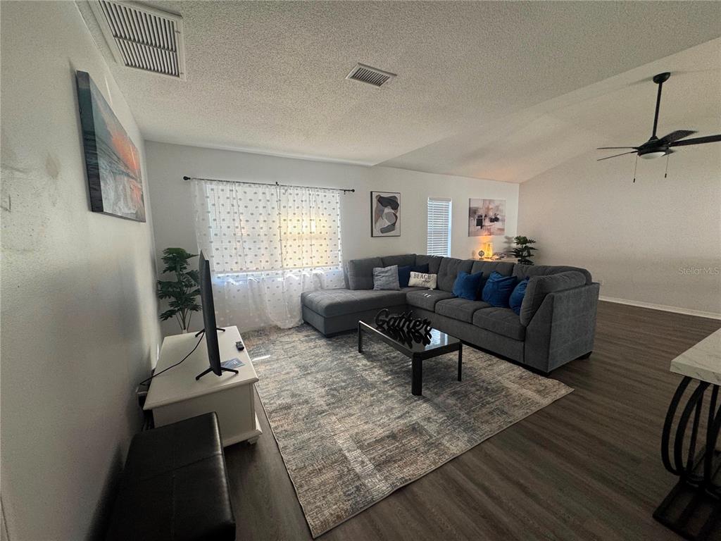 A living room features a gray sectional sofa, a coffee table, and a television — 12609 130TH STREET, LARGO, FL