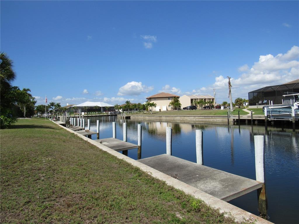 A concrete dock extends into a canal lined with houses and palm trees — 2818 & 2824 MAGDALINA DRIVE, PUNTA GORDA, FL