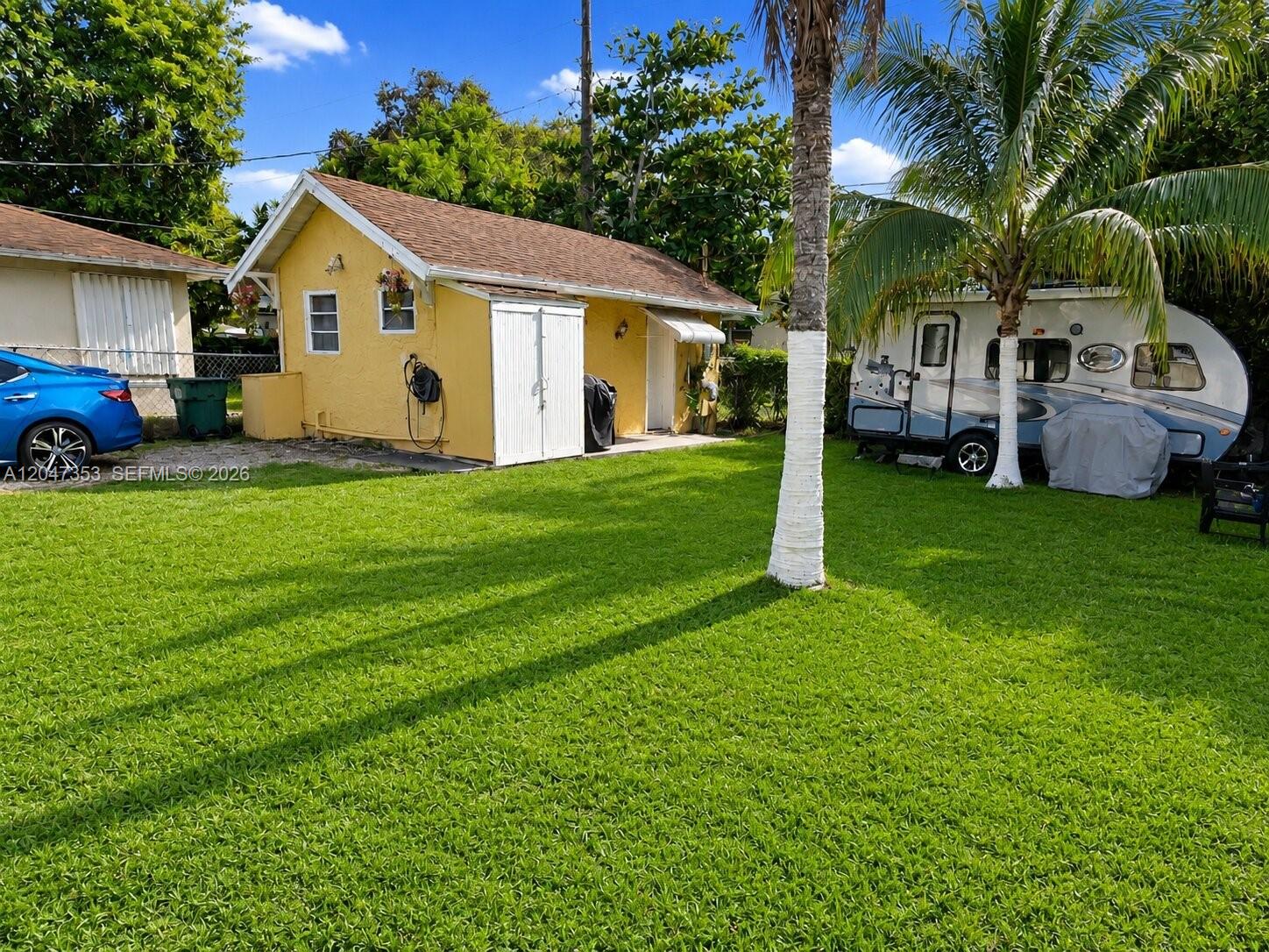 A yellow detached structure sits in a grassy yard next to a parked travel trailer — 6926 NW 4th Ave, Miami FL 33150, MIAMI, FL