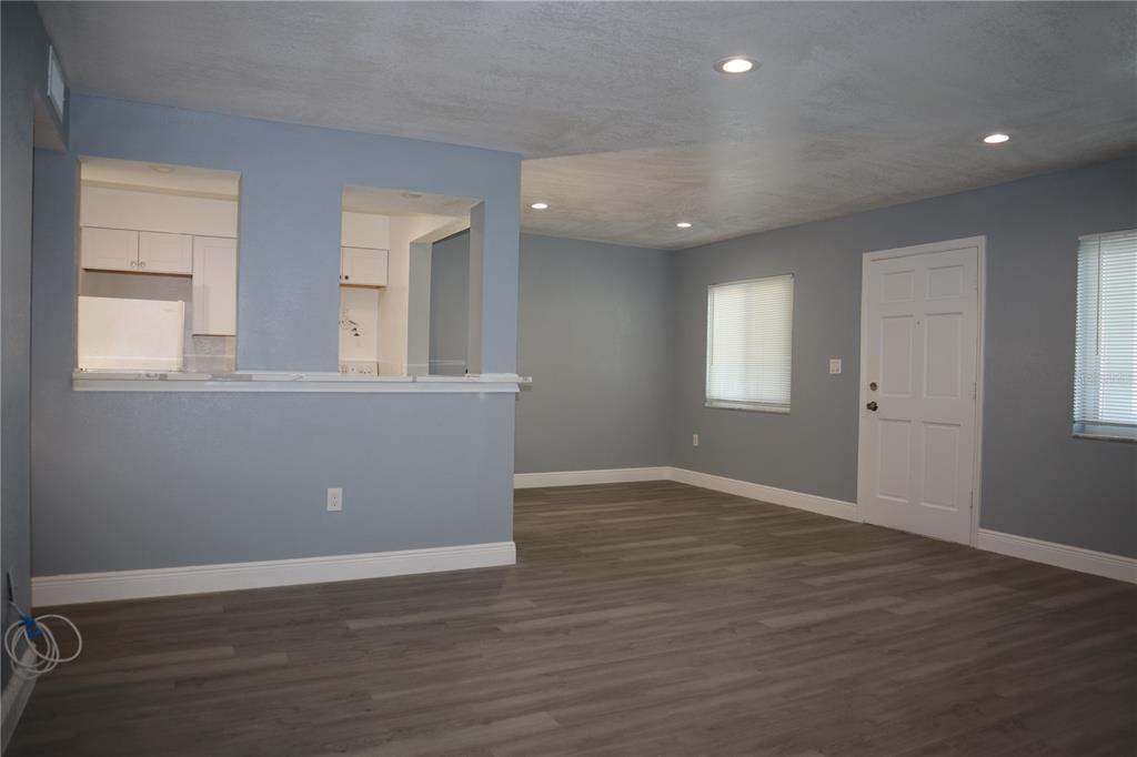 An open-concept living area features gray walls, wood-look flooring, recessed lighting, and a kitchen pass-through — 350 79TH AVENUE N UNIT 236, ST PETERSBURG, FL