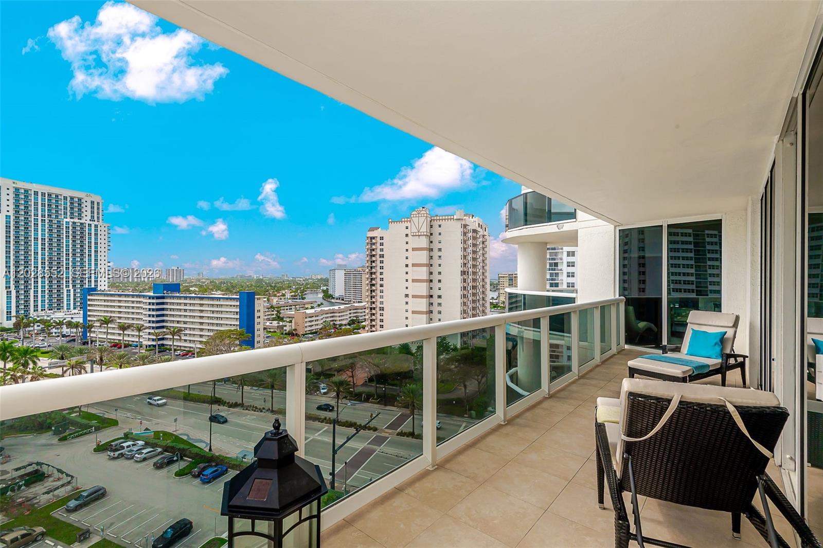 A balcony with tiled flooring, glass railings, and outdoor seating overlooks a city street view — 1850 S Ocean Dr # 1105, Hallandale Beach FL 33009, HALLANDALE BEACH, FL