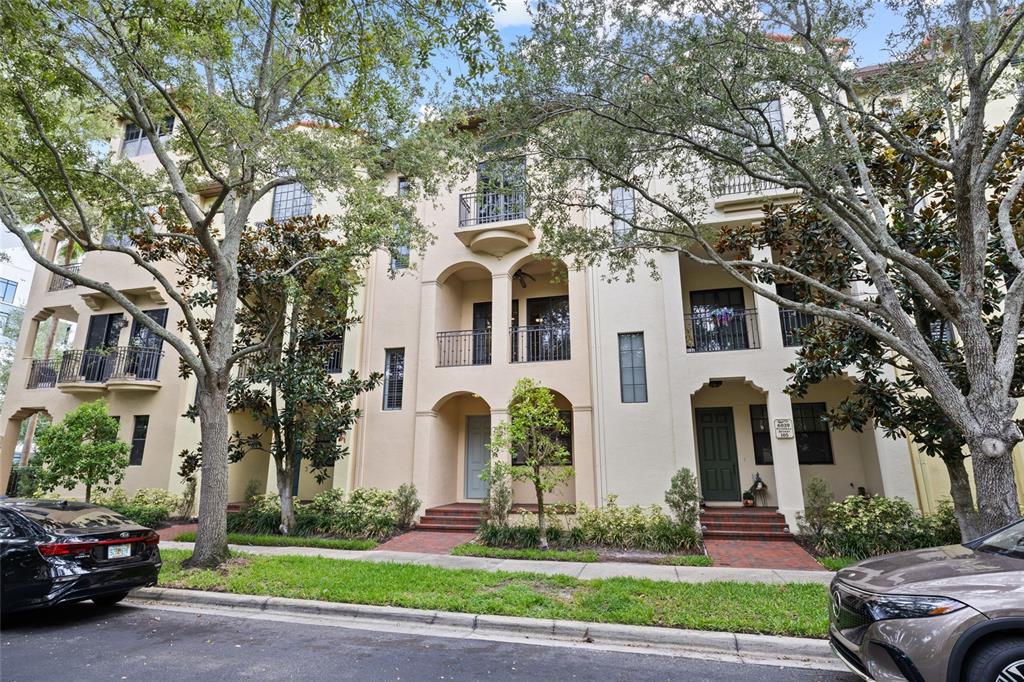 A multi-story townhouse complex with arched entryways, balconies, and mature trees in front — 6039 PRINTERY STREET UNIT 106, TAMPA, FL