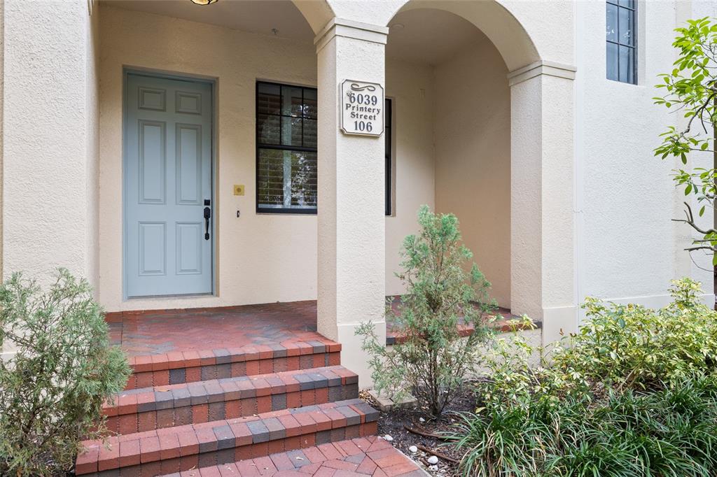 A light blue front door sits at the top of brick steps under an archway — 6039 PRINTERY STREET UNIT 106, TAMPA, FL