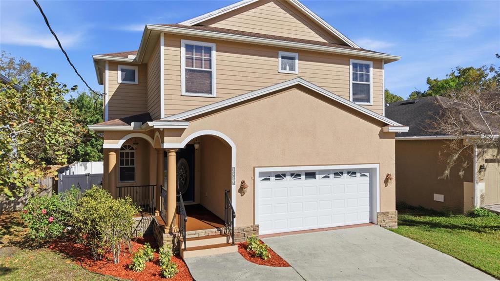A two-story house with tan siding and stucco, a front porch, and a two-car garage — 7504 S WEST SHORE BOULEVARD, TAMPA, FL